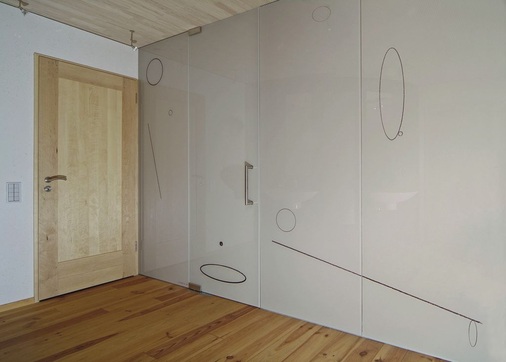 Eine raumhohe Glaspaneele mit integrierter Tür trennt das Bad vom angrenzenden Schlafzimmer
