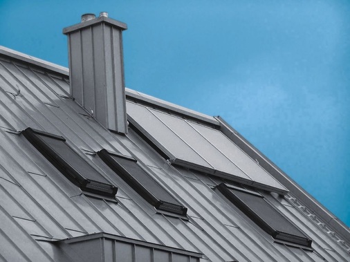 Dachdetail eines Wohnhauses mit integriertem Schornsteinkopf und Dachfenstern