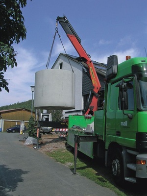 Der Betonbehälter wird mit dem LKW-Kran des Herstellers in die vorbereitete Baugrube abgelassen