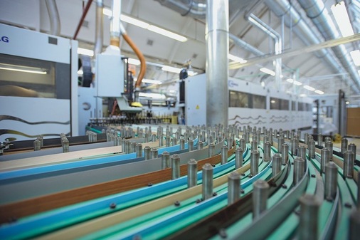 In der Formatstraße ­erhalten die Bauteile ihr exaktes Format. Gleichzeitig werden Kanten aus verschiedenen Materialien — die auf Rollen gelagert sind — mit PU-Leim ­angebracht, damit sie später auch wasserfest sind