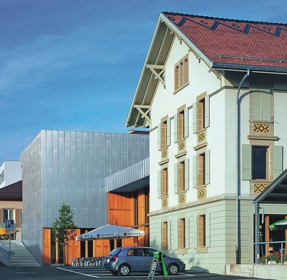Hotel de VilleTitanzink-Fassade in Bussigny bei Lausanne: Zwei völlig unterschiedliche Bauepochen und Stile verbinden und verschachteln das Hotel de Ville. ­Eine hinterlüftete Winkelfalzfassade aus walzblankem Titanzink dominiert den Hauptkubus. Fachbetrieb: Deléderray Toitures SA aus Renens