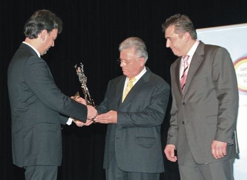 Als Zeichen der Dankbarkeit überreichten Hauptgeschäftsführer Dr. Schwarz (l.) und Landesinnungsmeister Hilpert (r.), Ehrenlandes­innungsmeister Werner Obermeier eine Skulptur mit dem bayerischen Löwen und den kunstvoll eingearbeiteten Buchstaben FVSHK