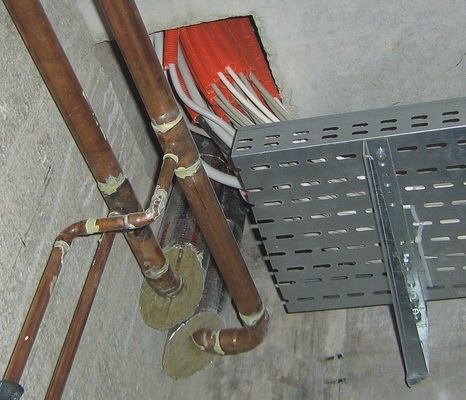3 Kabel laufen vom Schaltschrank auf ­offenen Pritschen unter den Decken der Treppenraumzugänge zu den Schächten.