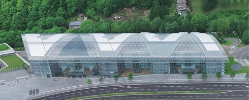 Das Gebäude der Luxemburger Investitionsbank wölbt sich in Hanglage. Unter der schützenden Hülle aus Glas und Aluminium zeichnen sich die V-förmig angeordneten Innengebäude ab.