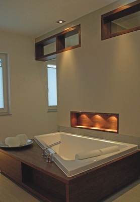 12 Die Duravit-­Paiova-Badewanne wird durch Down­lights in Szene ­gesetzt. Die beleuchte Holznische sorgt für sanftes Stimmungslicht.