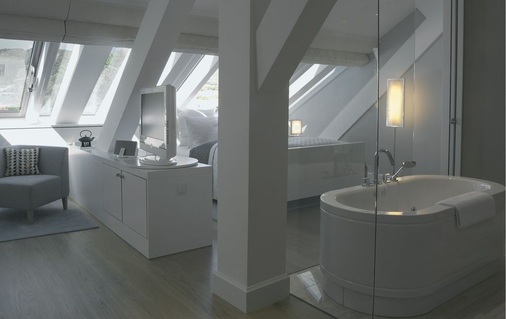 2 Glaswände statt Mauern lassen die Grenzen verschwimmen. Die ­freistehende Wanne von bette bildet den Übergang zwischen ­Ruhezone Schlafen und den Aktivzonen des Badezimmers.