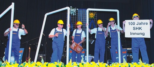 Zur Musik von „Ich bin Klempner von Beruf“ fertigten Innungsmitglieder die Zahl 100 aus Rohrstücken.