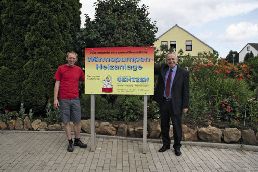 SHK-Meister Oliver Gentzen (links) und Michael Washausen, Schulungsleiter Uni-­Electronic, mit dem Baustellenschild: Wärmepumpen sind eine Spezialität des ­Handwerksbetriebs.