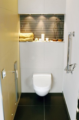 9 WC mit seitlicher Spülbetätigung per Knopfdruck. Papier und Bürste verschwinden in der Wand, der seitliche Haltegriff funktioniert als Zeitungshalter.