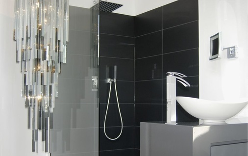 Schlicht präsentiert sich die Dusche — im Kontrast dazu der Art-Deco-Leuchter.