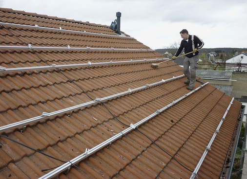 Sorgfalt ist oberstes Gebot: Bevor die Solarmodule aufgelegt und verkabelt werden, säubert der Installateur die Dachfläche. - © Priogo AG
