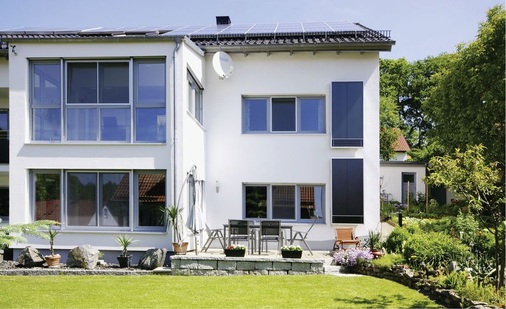 Luftkollektoren von Grammer Solar an der Außenwand des Gebäudes rechts. Im unteren Bereich der Kollektoren hebt sich das PV-Feld optisch ab.