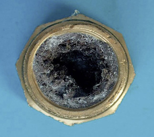 <p>
Verschluss im Anschlussbereich eines kathodisch geschützten Trinkwasserspeicherbehälters. Der dunkle Belag besteht vorwiegend aus Kalziumkarbonat mit eingelagertem Kupfer, welches die Ablagerung elektrisch leitend hält.
</p>
