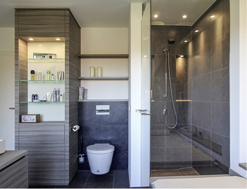 Blick auf insgesamt vier eingebaute 12-V- Niederspannungs-Halogen-Downlights (20&nbsp;W) im Duschbereich sowie auf die Beleuchtung der Badeutensilien in dem extra entworfenen Schrank mit zwei Downlights.
