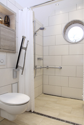 
Ein Nischenschrank mit Regalfach über dem WC als optisches Pendant zum Waschplatz nutzt die Vorwand als Stauraum.
