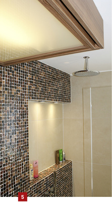 
Die Deckenschiene verschwindet in einer Fuge im abgehängten Baldachin. Eine hinterleuchtete Glasscheibe sorgt für angenehm warmes Licht im Duschbereich.



