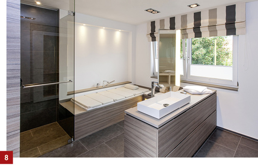 
Die Dusche öffnet sich zum Raum. Die Glasabtrennung an der Wanne wurde im Bereich der Wanne rückseitig im Ton der Fliesen lackiert. 



