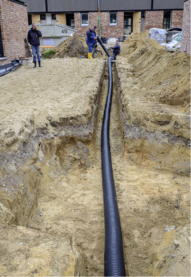 
Die PUR-gedämmten Rohre sind aufgrund ihrer höheren Steifigkeit schwerer zu verarbeiten und bieten sich daher eher für direkte Verbindungen an. Im Vordergrund ein bereits ausgebaggertes Kopfloch.



