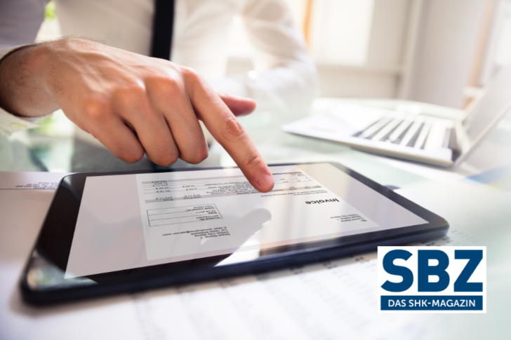 Person, die mit einem Tablet eine Rechnung betrachtet, mit dem Logo der SBZ Das SHK-Magazin in der Ecke. - © Adobe Stock / Andrey Popov
