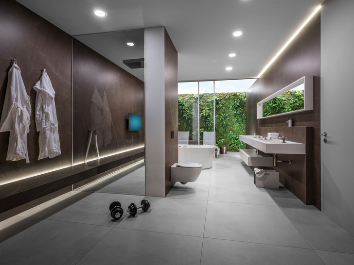 Die raumhohe Vorwand ermöglicht Platz für eine ­Regendusche und für die Installationstechnik. ­Zugleich gibt sie dem langgezogenen Raum Struktur.