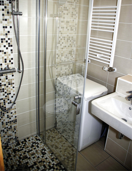 Bodengleiches ­Duschen im Minibad eines Berliner ­Plattenbaus: Die Entwässerungstechnik verbirgt sich im Boden und in der Wand hinter der Waschmaschine.