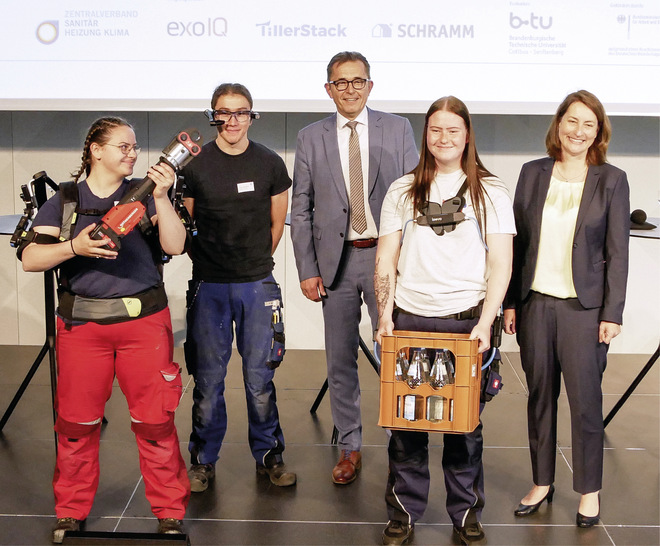 Forschungsprojekt Handwerksgeselle 4.0 abgeschlossen: Leonie Gebers (Bundesministerium für Arbeit und Soziales, rechts) und ZVSHK-Präsident Michael Hilpert (Mitte) mit Jugendlichen, die mit Exoskelett und Datenbrille 
praktische Erfahrungen gesammelt haben. - © Bild: SBZ / Dietrich
