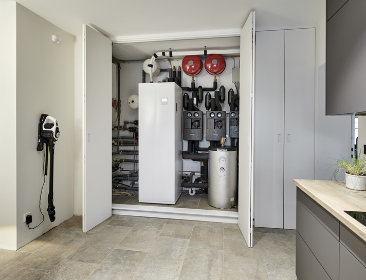  Haustechnikzentrale im Hauswirtschaftsraum: Blick auf die kompakte Inneneinheit der Luft/Wasser-Wärmepumpe „Syshp Mini Split“. Der 240-l-Brauchwasserspeicher ist integriert, rechts daneben ein zusätzlicher 100-l-Pufferspeicher als „hydraulische Weiche“.