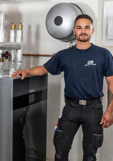 Heizungsinstallateur Paul Hamberger mit der Wärmepumpen-Inneneinheit Logatherm WLW186i-12 TP70 von Buderus.