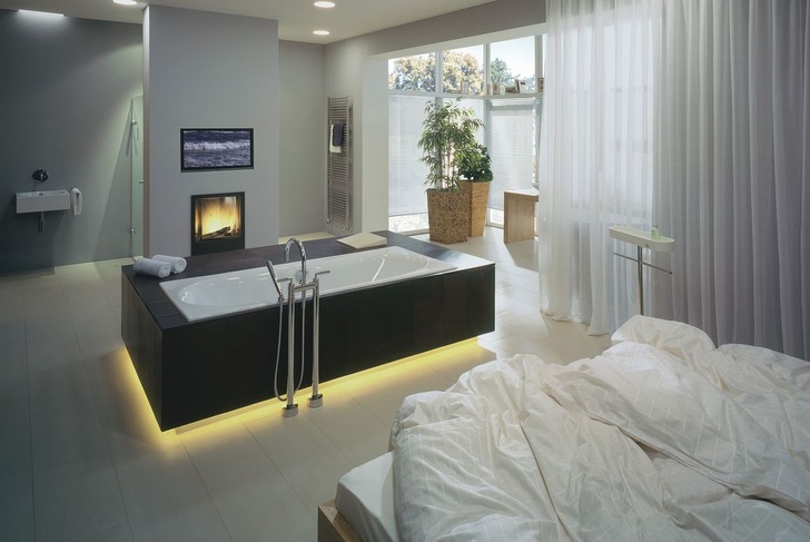 1 In einer Achse angeordnet sind Bett, Wanne und die Dusche — optisch durch einen Kamin abgeteilt. Der Waschplatz im Wintergarten bietet mittels Vorhang Intimität. Lediglich das WC ist räumlich abgeteilt. Kommunikativ liegen sich Bett und Wanne mit beheizbarer Liegefläche gegenüber.