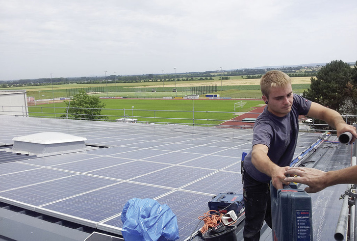 Handwerker packen zu: Sanierung des Daches einer Turnhalle in Zülpich. Das Asbestdach wurde durch Trapezblech und Solarmodule ersetzt.