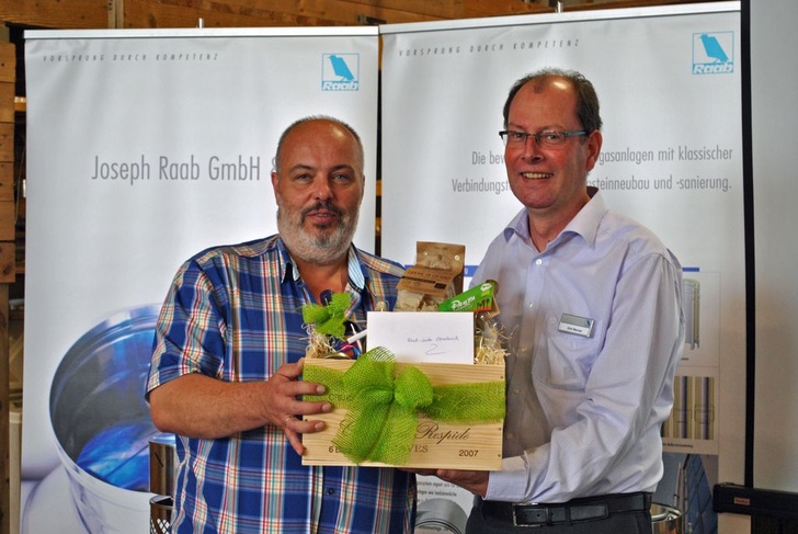 Feierliche Eröffnung des Raab-Centers Osnabrück: Dirk Werner (r.), Verkaufsleiter Nord der Raab-Gruppe, überreicht Detlef Wartemann, Geschäftsführer der Wartemann & Klose Schornsteintechnik GmbH sowie des Wartemann Fachgroßhandels, einen Präsentkorb.