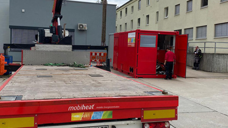 Eine 600 kW mobiheat Heizzentrale sorgt – witterungsgeschützt im Container – für die temporäre Beheizung des Wartungsgebäudekomplexes eines schwäbischen Automobilherstellers.
