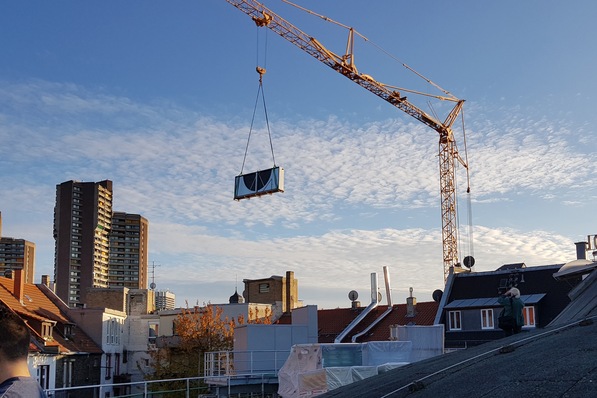 Einen halben Rotations-Wärmeübertrager am Haken: Die neue Lüftungsanlage wurde außen auf einer Stahlkonstruktion installiert.