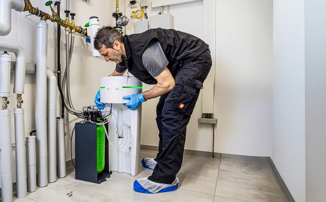 SHK-Fachkraft installiert ein fortschrittliches Wasseraufbereitungssystem in einem Technikraum, um eine effiziente Filtration und verbesserte Trinkwasserhygiene zu gewährleisten. - © Bild: Grünbeck / Bernd Jaufmann