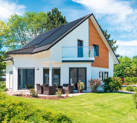 „Zweistöckiges modernes Wohngebäude mit dreieckigem Dach, ausgestattet mit Solarpanelen zur nachhaltigen Energieversorgung. Das Bild zeigt weiterhin eine gepflegte Außenanlage und Terrassenmöbel, die effektive Planung und Installation im Bereich Heizungs- und Klimatechnik sowie neue Entwicklungen in der Wasseraufbereitung für energieeffiziente Lösungen im Bauwesen verdeutlichen. - © Bild: Paradigma