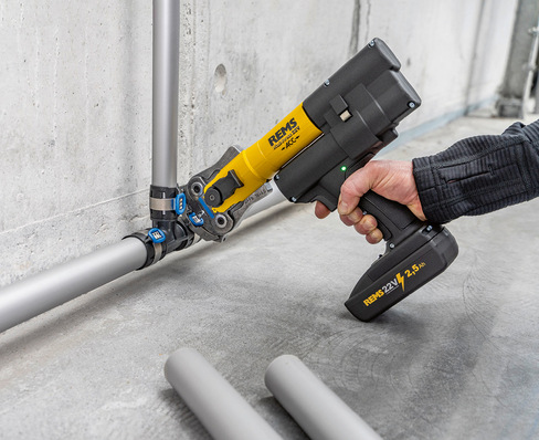 „Fachkraft installiert Kupferrohre mithilfe eines gelb-schwarzen Elektro-Werkzeugs an einer Betonwand, zeigt moderne Techniken bei der Sanitär- und Installationstechnik. - © Bild: Rems / 2FF Film&Foto Produktion