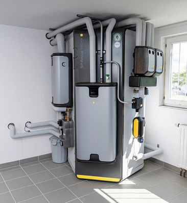 Moderne Heizungsanlage mit mehreren Rohren und Geräten, die in einem hellen Hauswirtschaftsraum mit Fliesenboden installiert sind. - © Bild: Ritter Energie / Sebastian Berger